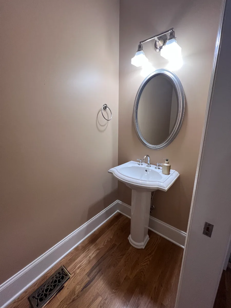 A modern-elegant powder room in Watkins Creek, Franklin TN 37067. Ripe Olive and Champagne cabinetry, Mikado Cemento quartz, Native Trails Morro vessel sink, and Delta Trinsic Matte Black by Sebring Design Build.