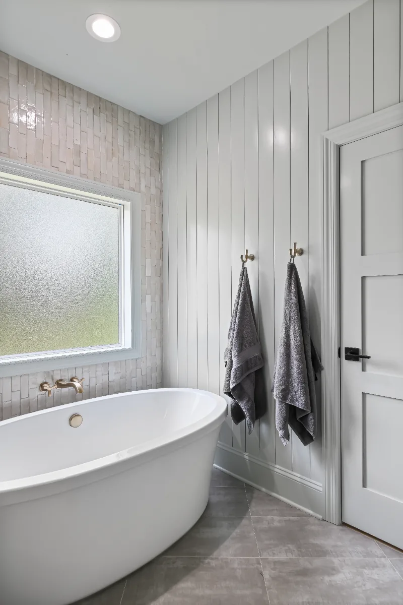 A modern-elegant primary bath in Watkins Creek, Franklin TN 37067. White Oak Flint Hills cabinetry, Mikado Calacatta Tree quartz, MTI freestanding tub, and Natural White Zellige shower walls by Sebring Design Build.