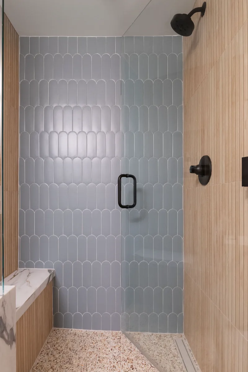A modern-functional basement guest bath in Bonbrook, Brentwood TN 37027. Kenridge Ribbon Maple shower walls, Parry Marine Blue fishscale accent tile, and Delta Okinetic Matte Black fixtures by Sebring Design Build.