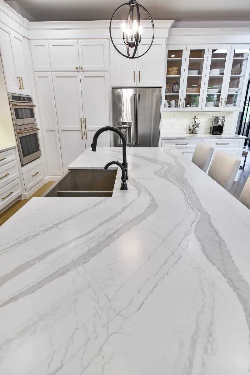 A transitional-elegant kitchen remodel in Franklin, TN. Snowbound and White Oak Sage cabinetry, Cambria Brittanicca Warm Matte quartz, and Zellige tile backsplash by Sebring Design Build.