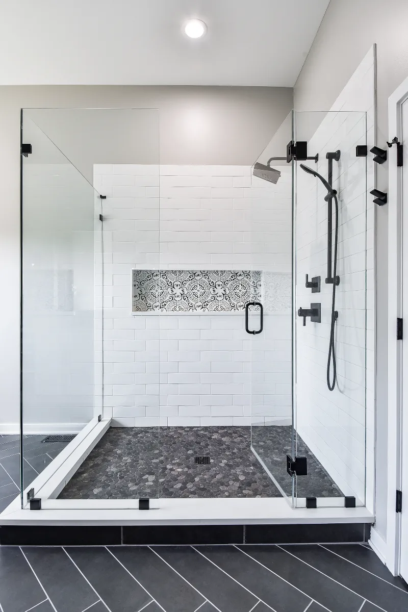 A modern-black-white primary bath remodel in Franklin, TN. Bellmont 1600 Studio White cabinetry, Cambria Deligatie quartz, Kohler Pivotal Matte Black, MTI Andrea tub, and MSI Kenzzi Paloma tile by Sebring Design Build.