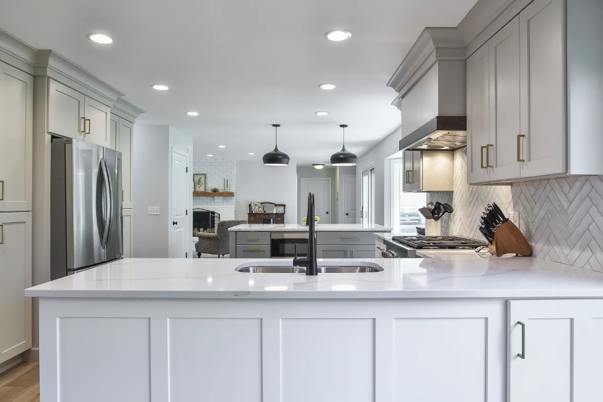 A Franklin, TN kitchen remodel with custom cabinetry in soft white, dune, and Puget Sound blue. Calacatta Aria quartz and Berenson Metro hardware by Sebring Design Build.