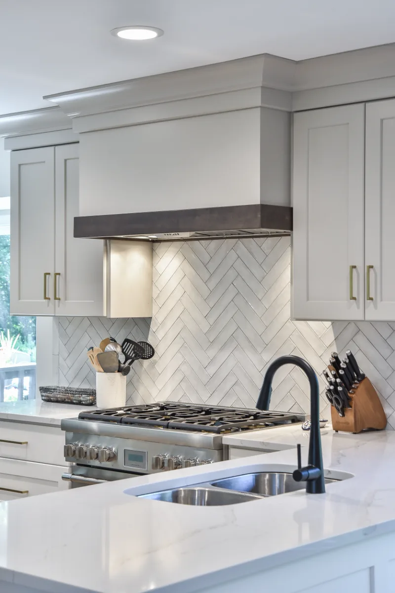 A Franklin, TN kitchen remodel with custom cabinetry in soft white, dune, and Puget Sound blue. Calacatta Aria quartz and Berenson Metro hardware by Sebring Design Build.