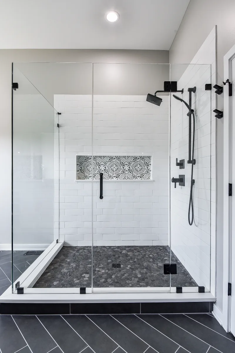 A modern-black-white primary bath remodel in Franklin, Tennessee. Bellmont Studio White cabinetry, Cambria Deligatie quartz, Kohler Pivotal Matte Black, and MSI Kenzzi Paloma accent tile by Sebring Design Build.