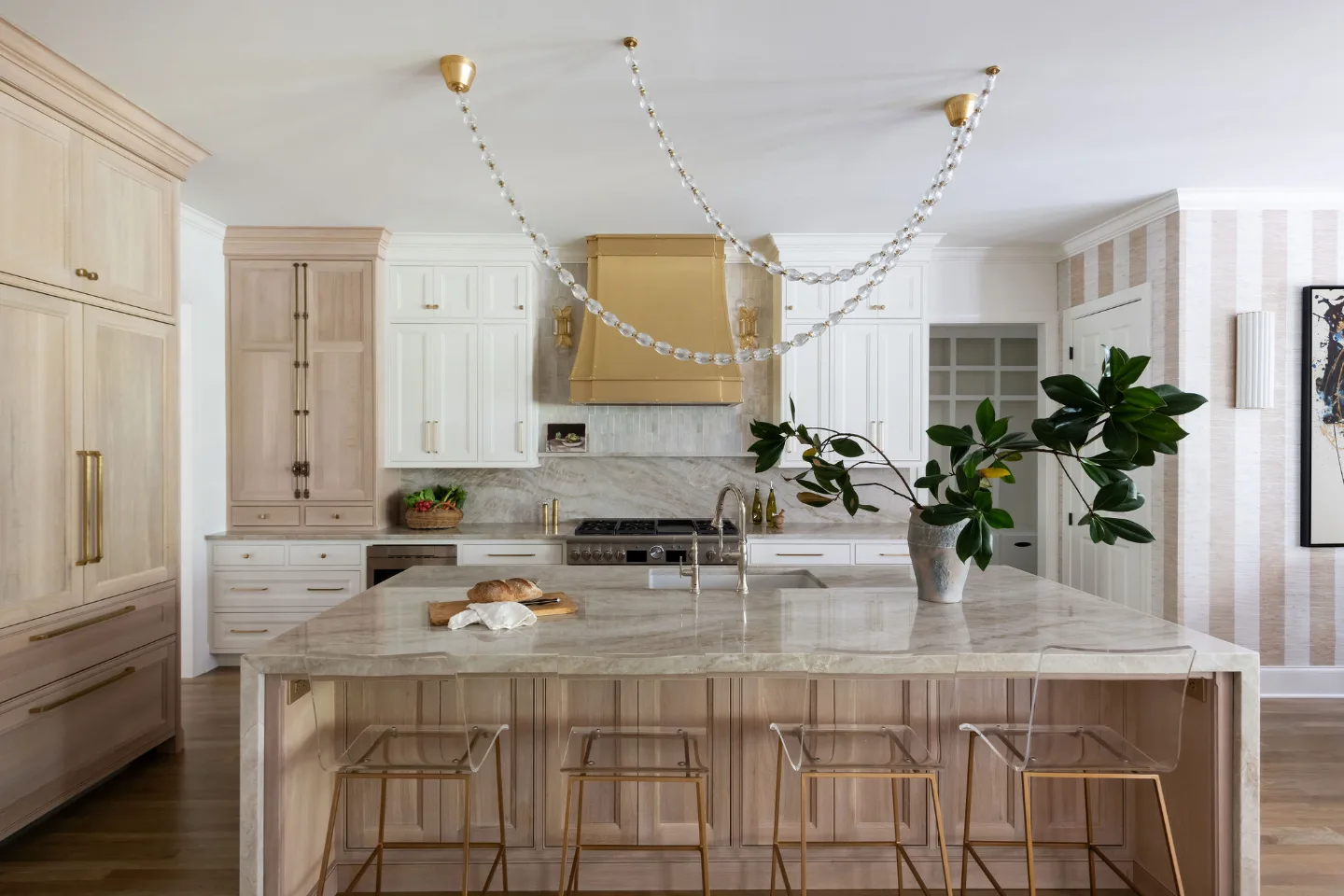 A modern-warm kitchen remodel in Westhaven, Franklin TN 37064. Custom brushed brass range hood, Dune and Tarragon cabinetry, Calcutta Castana quartz, and Natural White Zellige backsplash by Sebring Design Build.