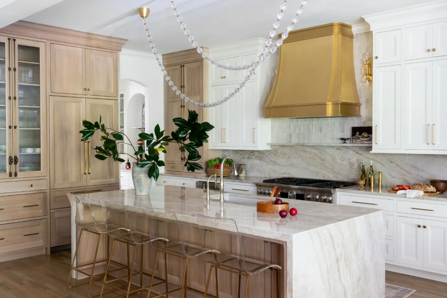 A modern-warm kitchen remodel in Westhaven, Franklin TN 37064. Custom brushed brass range hood, Dune and Tarragon cabinetry, Calcutta Castana quartz, and Natural White Zellige backsplash by Sebring Design Build.