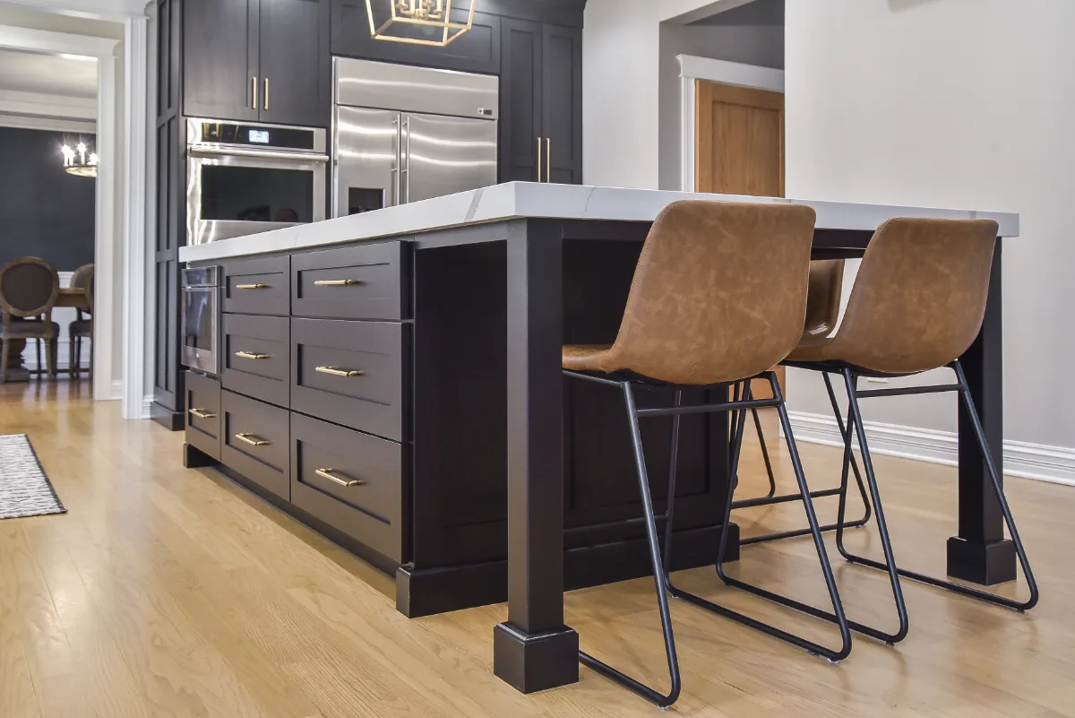 A modern-elegant kitchen, bar, and pantry remodel in Brentwood, TN. Shaker cabinetry in Ebony and Soft White, Corian Calcutta Natural quartz, and Kohler Brushed Moderne Brass fixtures by Sebring Design Build.