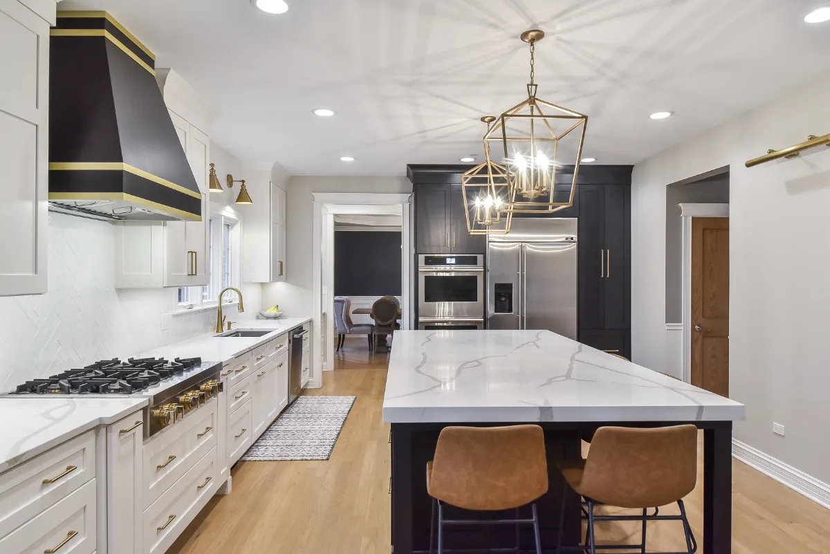 A modern-elegant kitchen, bar, and pantry remodel in Brentwood, TN. Shaker cabinetry in Ebony and Soft White, Corian Calcutta Natural quartz, and Kohler Brushed Moderne Brass fixtures by Sebring Design Build.