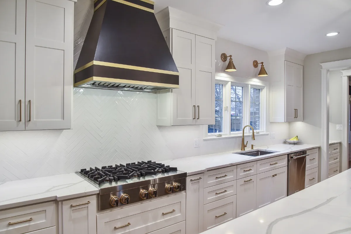 A modern-elegant kitchen, bar, and pantry remodel in Brentwood, TN. Shaker cabinetry in Ebony and Soft White, Corian Calcutta Natural quartz, and Kohler Brushed Moderne Brass fixtures by Sebring Design Build.
