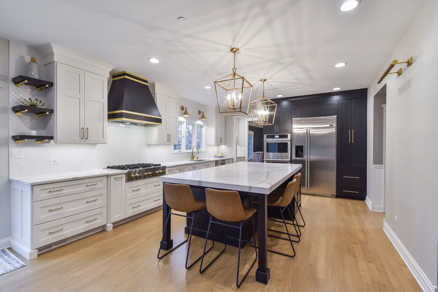 A modern-elegant kitchen, bar, and pantry remodel in Brentwood, TN. Shaker cabinetry in Ebony and Soft White, Corian Calcutta Natural quartz, and Kohler Brushed Moderne Brass fixtures by Sebring Design Build.