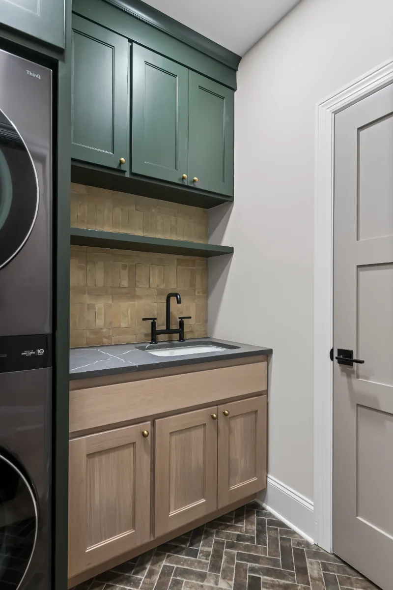 Laundry remodel in Watkins Creek, TN. Sebring Design Build transformed this Watkins Creek laundry room in Franklin, Tennessee with Ripe Olive and Champagne cabinetry, Mikado Cemento quartz, a Kohler Purist bridge faucet.