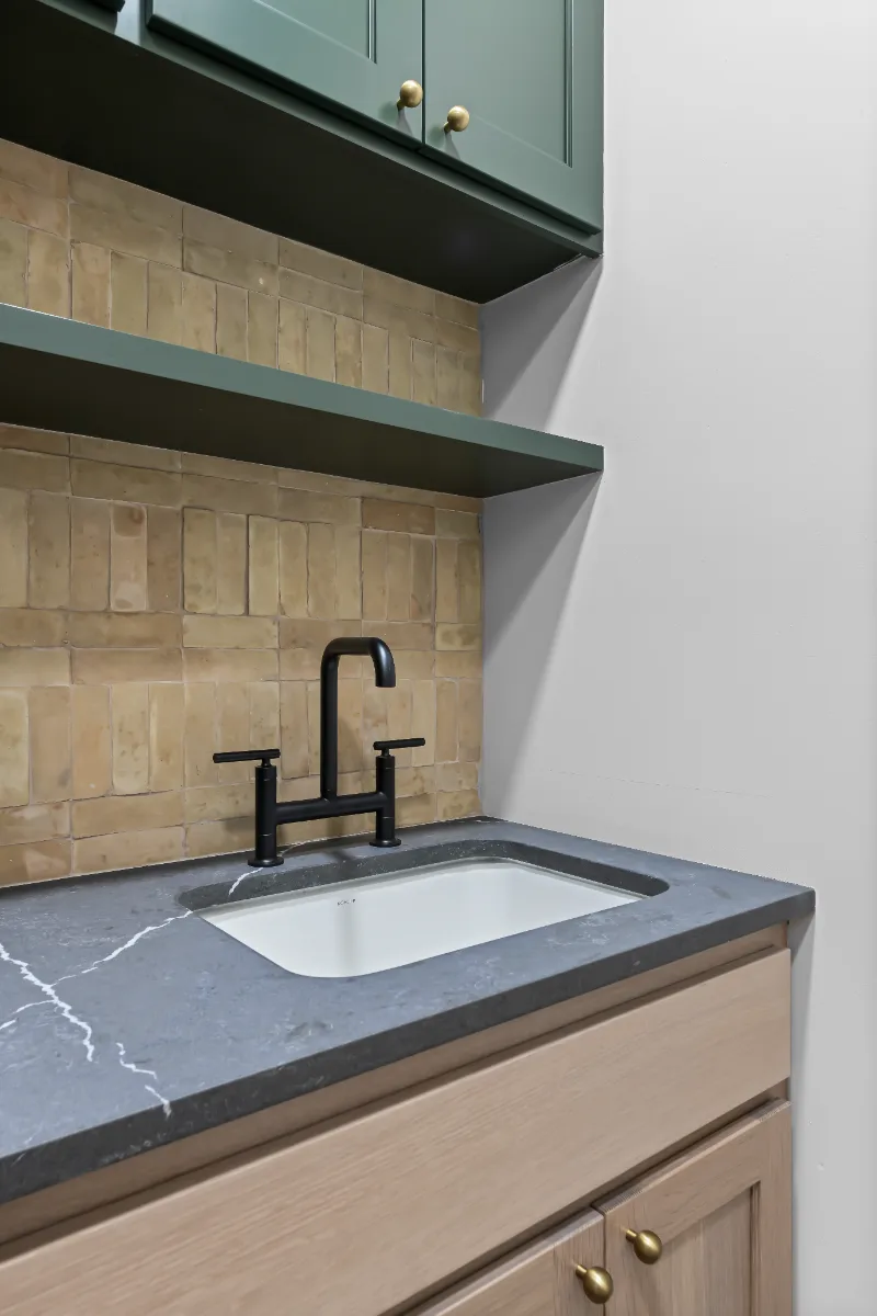 Laundry remodel in Watkins Creek, TN. Sebring Design Build transformed this Watkins Creek laundry room in Franklin, Tennessee with Ripe Olive and Champagne cabinetry, Mikado Cemento quartz, a Kohler Purist bridge faucet.