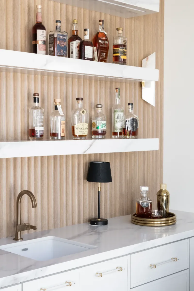 Bar remodel in Westhaven, TN. Sebring Design Build designed this Westhaven bar with MSI Calacatta Castana quartz surfaces, Rift White Oak elements, Brizo Luxe Gold fixtures, and a Franke prep sink.