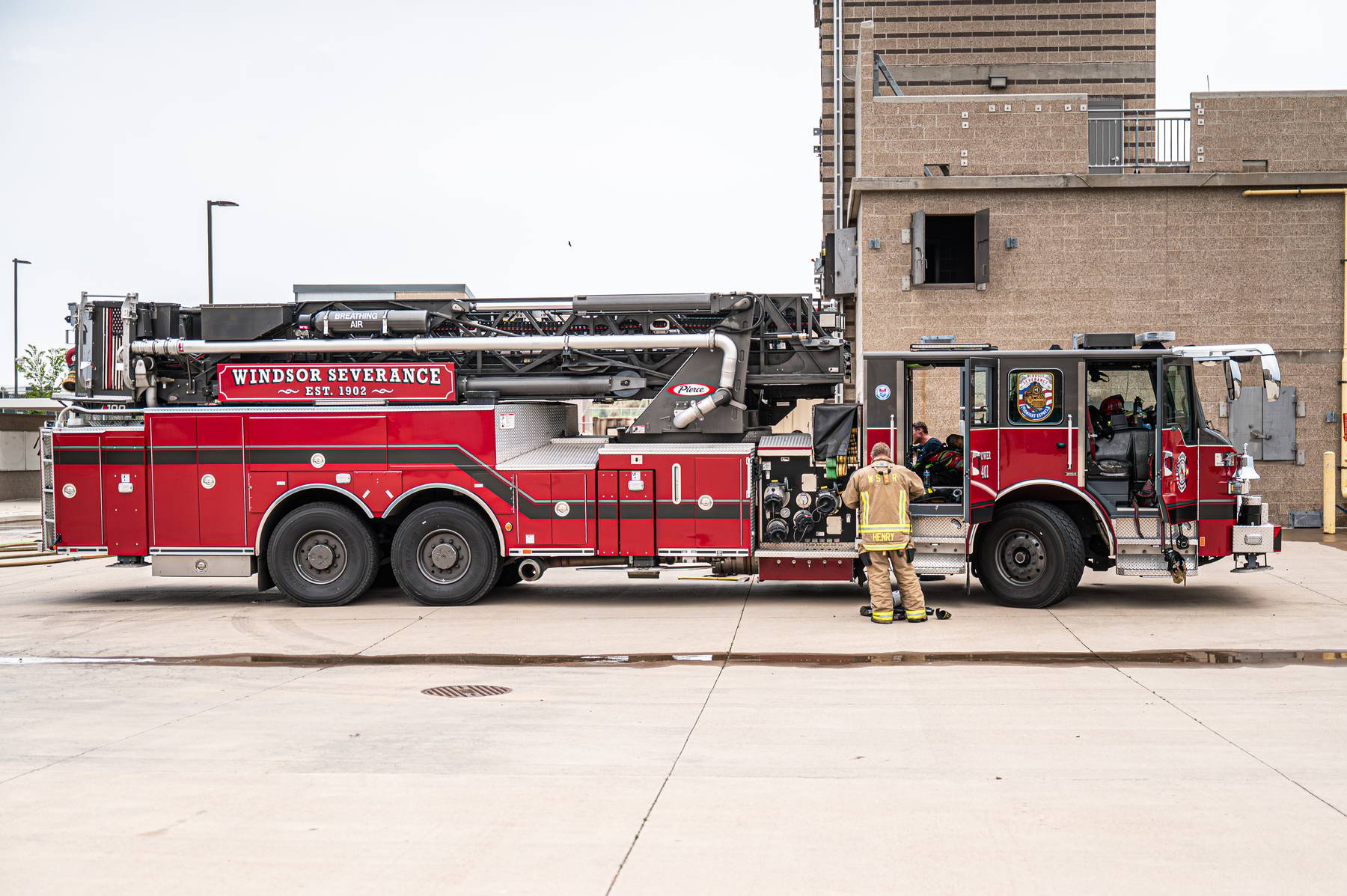 Red Windsor Severance fire truck parked with firefighters near its open compartments.