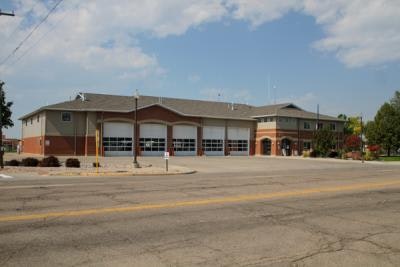Fire station building with multiple garage doors under a partly cloudy sky.