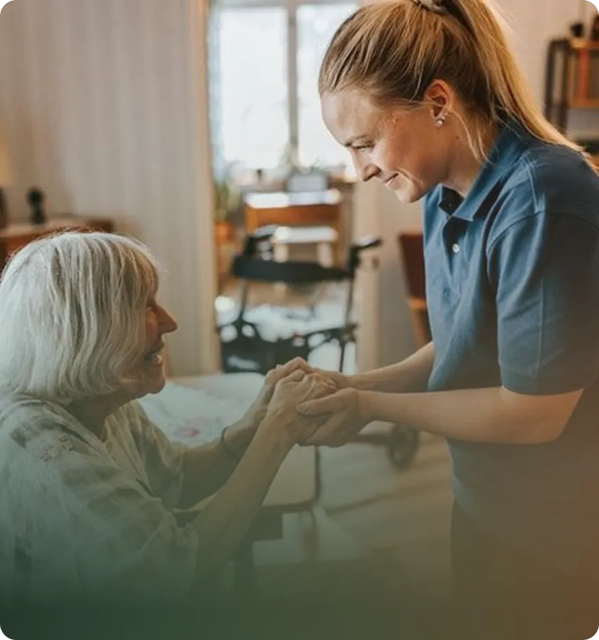 A caregiver holding hands with an elderly woman, smiling