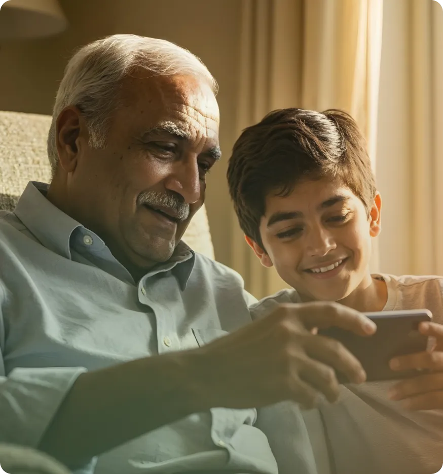 An older man and a boy looking at a phone together, smiling