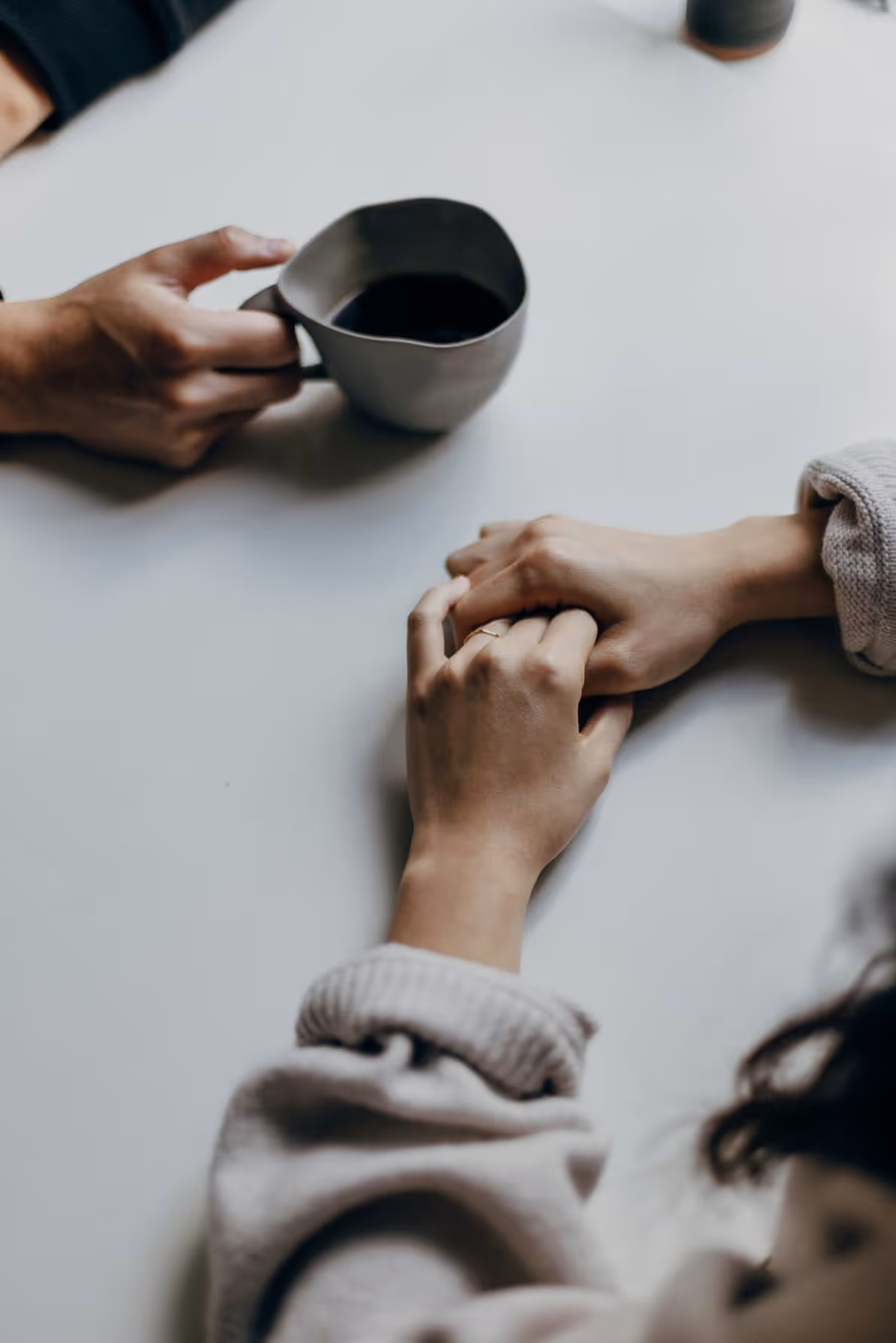 Image of two hands and coffee sitting on a table
