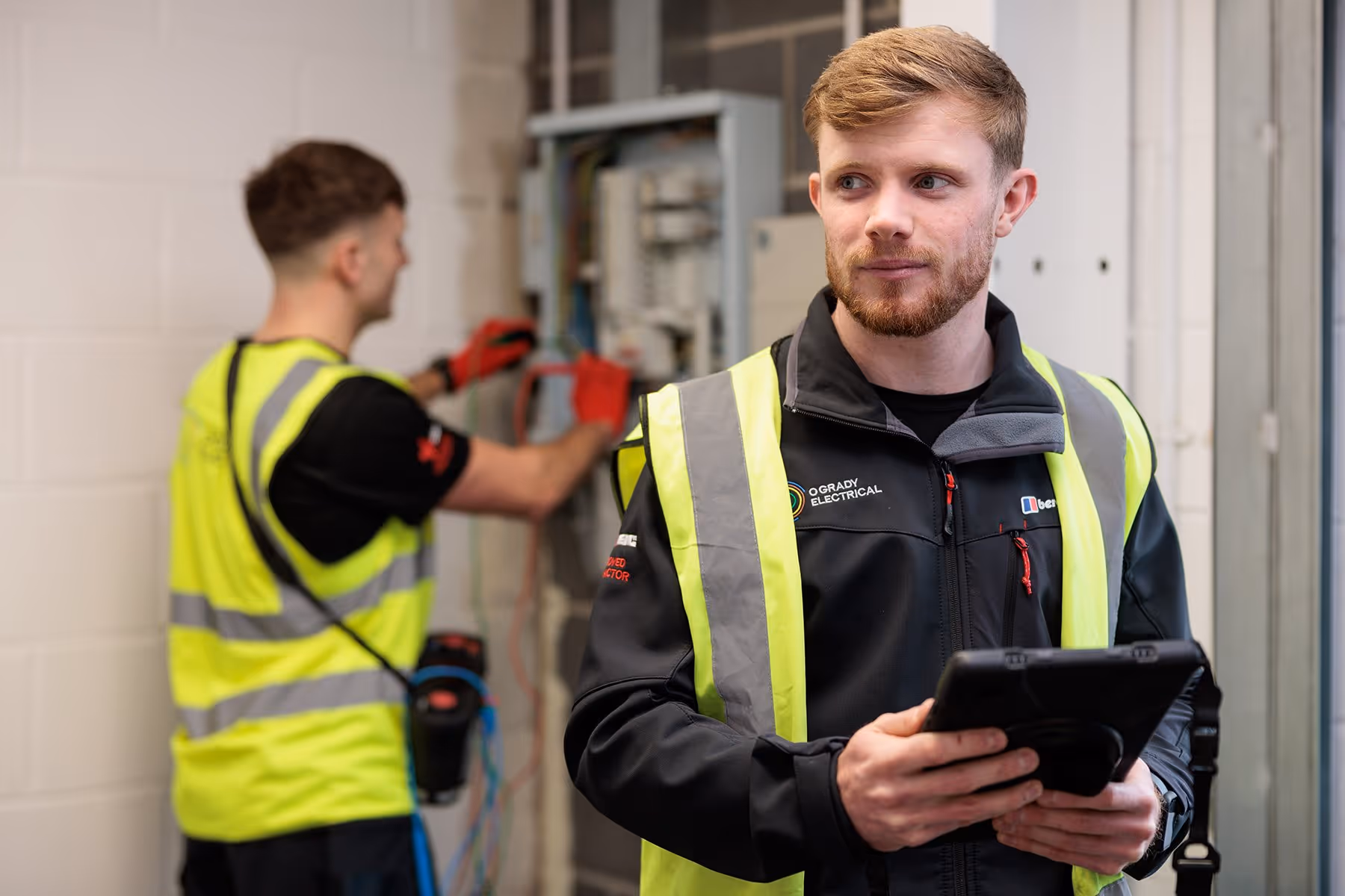 Two O'Grady Electricians working together within an industrial building.