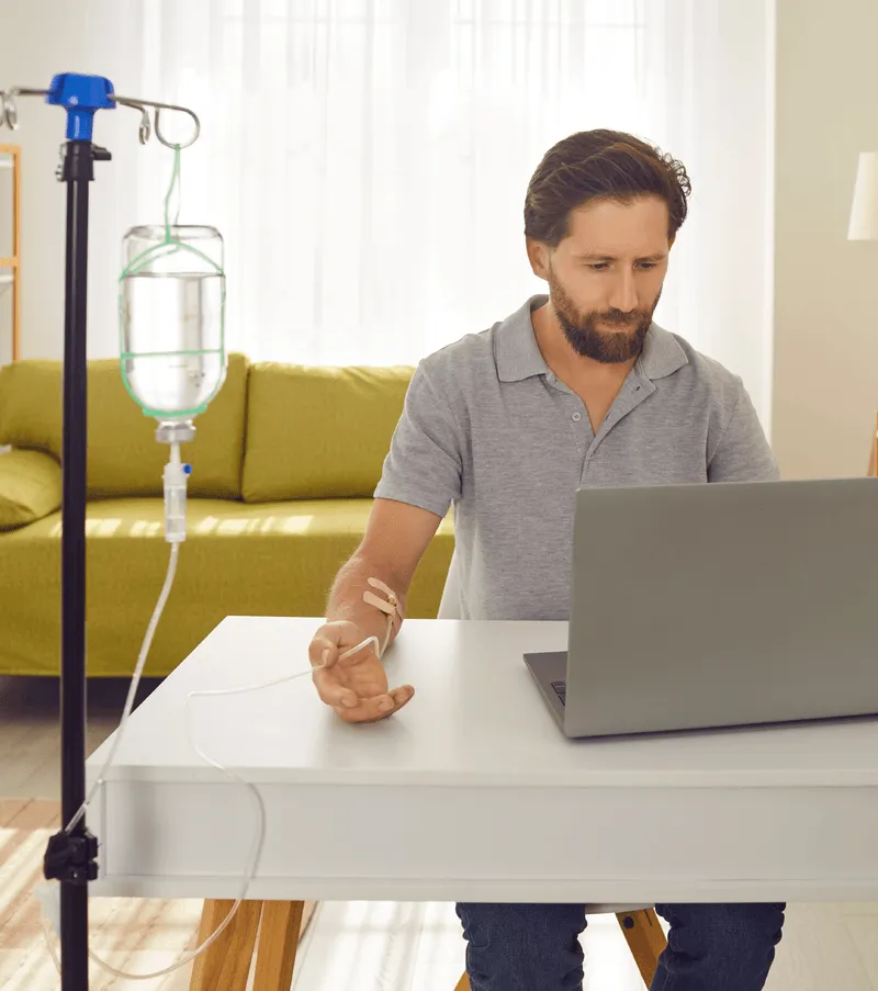 Man sitting at table working while getting infusion therapy