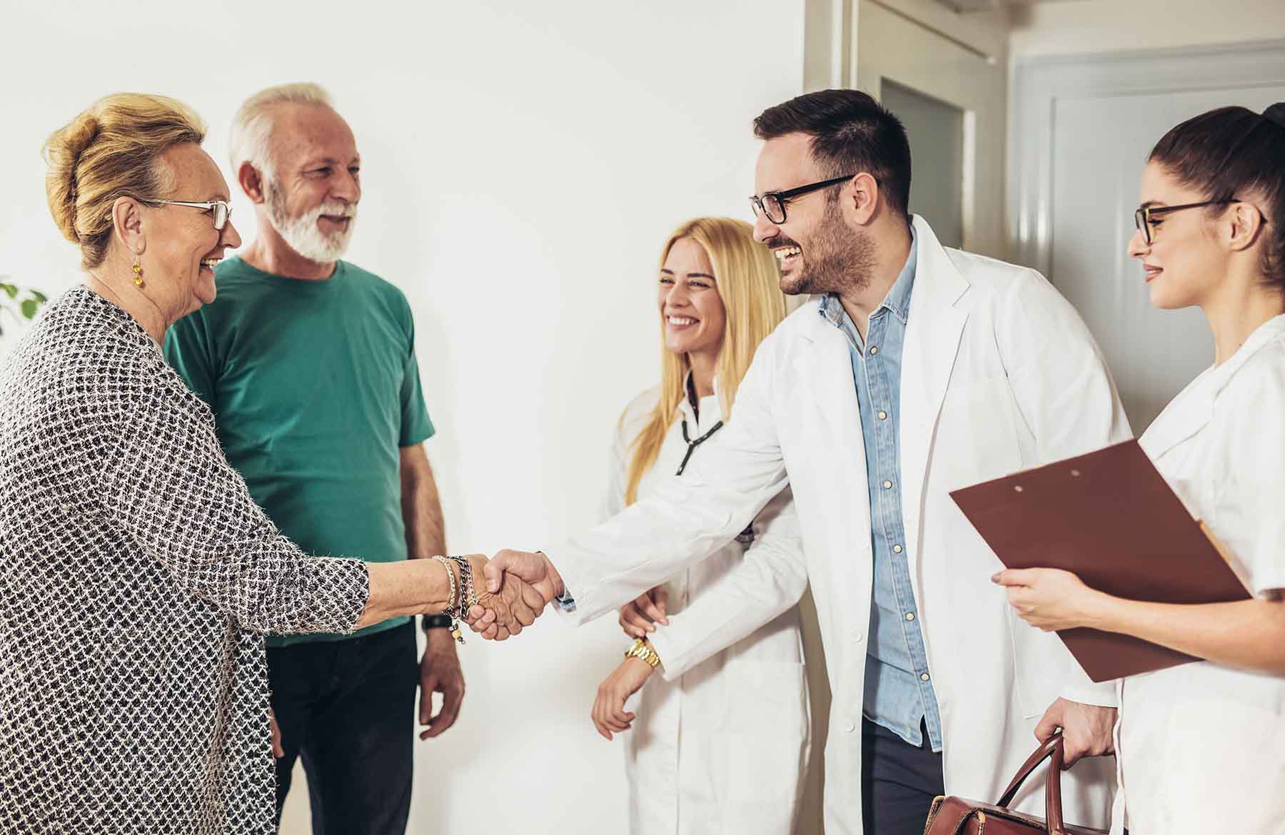 Patients visiting doctors office shaking hands with primary care physician