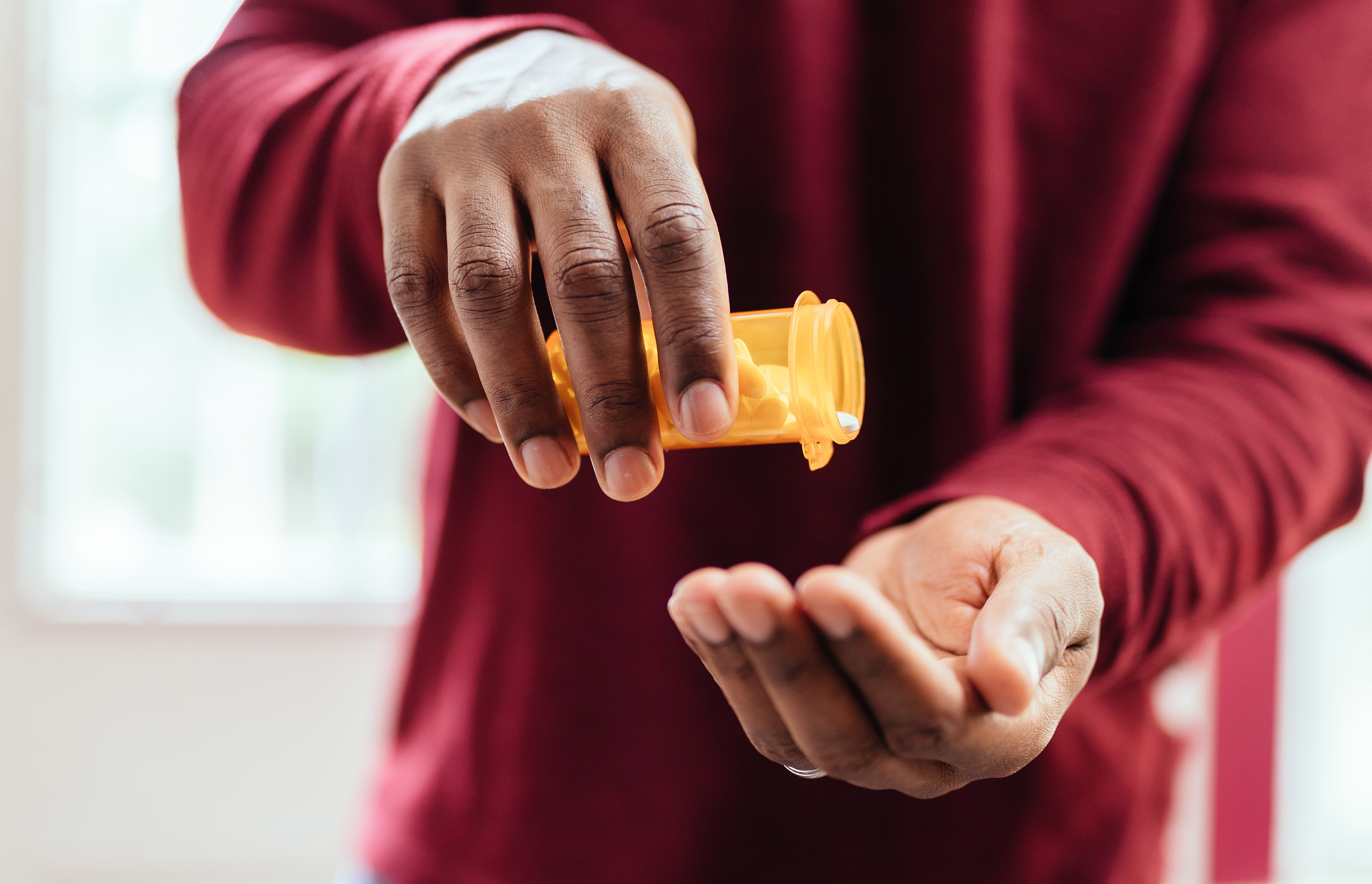 Man pouring out medication from prescription bottle