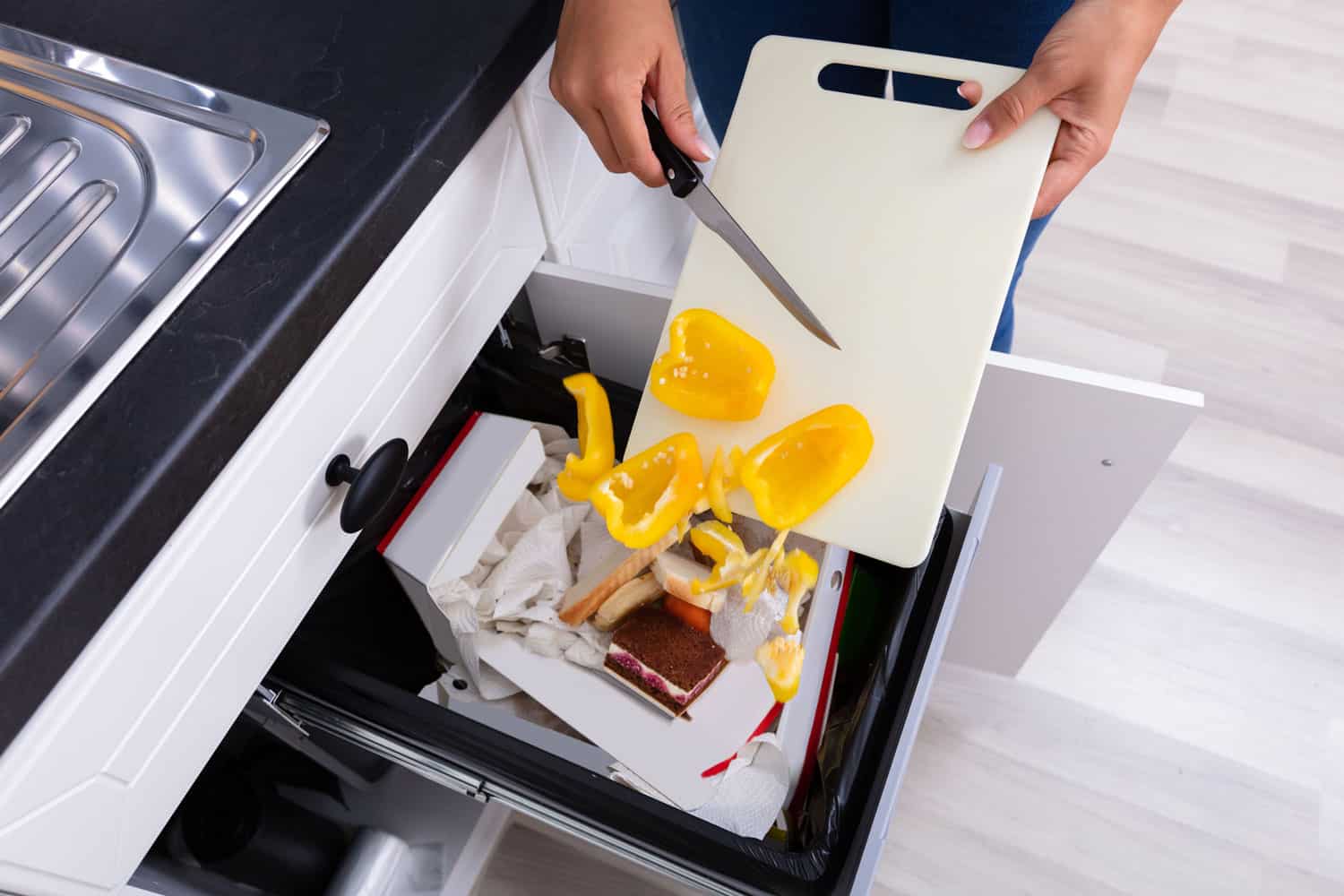 woman throwing vegetables in trashcan