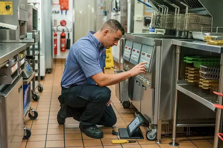 man fixing air fryer in commercial kitchen