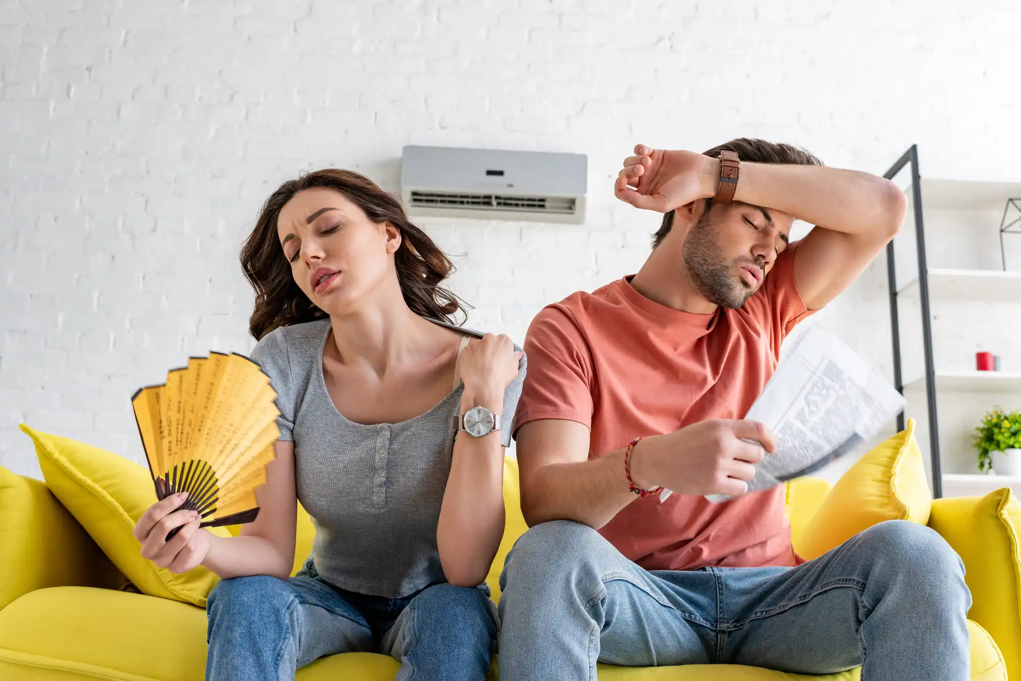 Couple suffering from heat due to a broken air conditioner