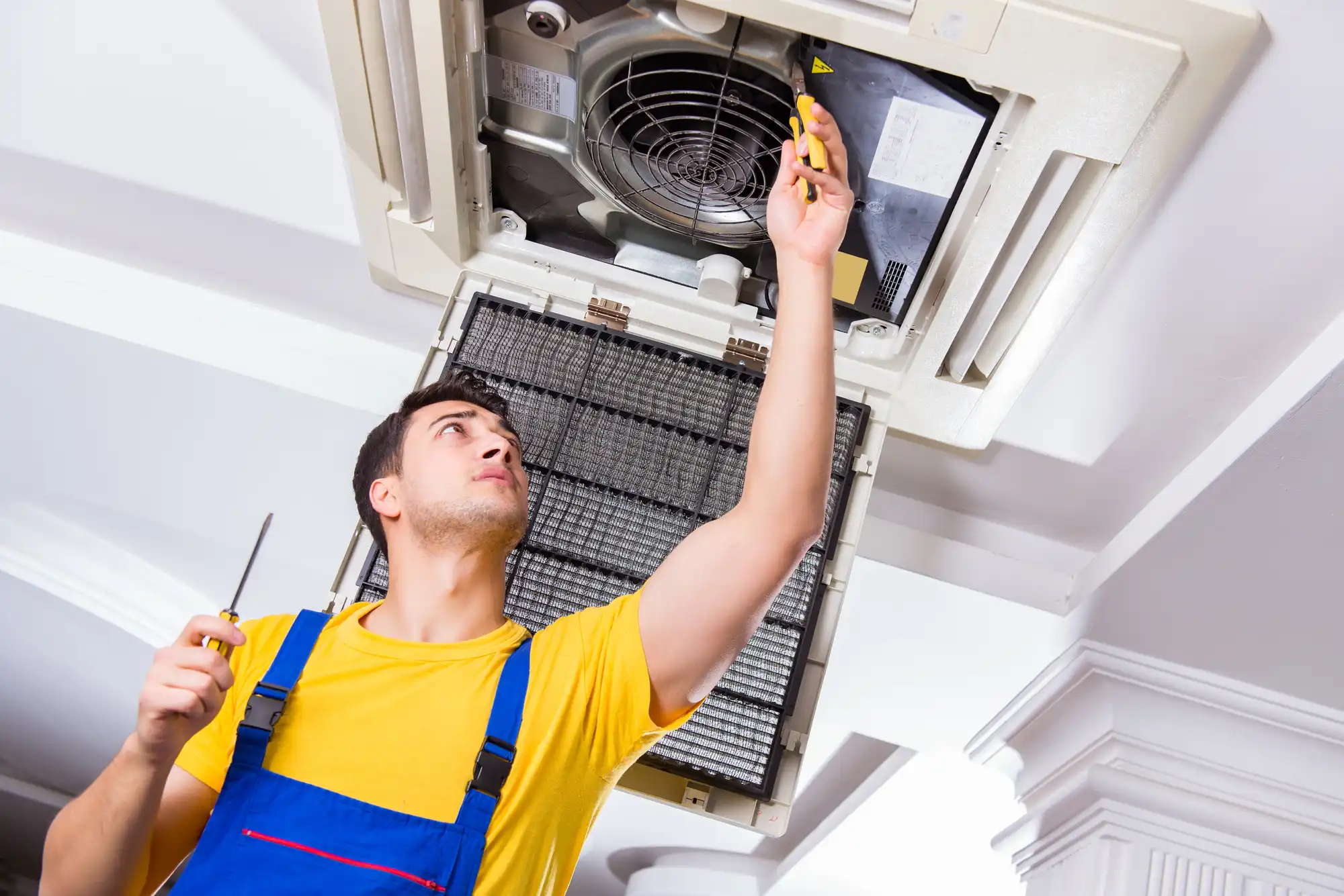 An expert is fixing the air conditioner on the ceiling