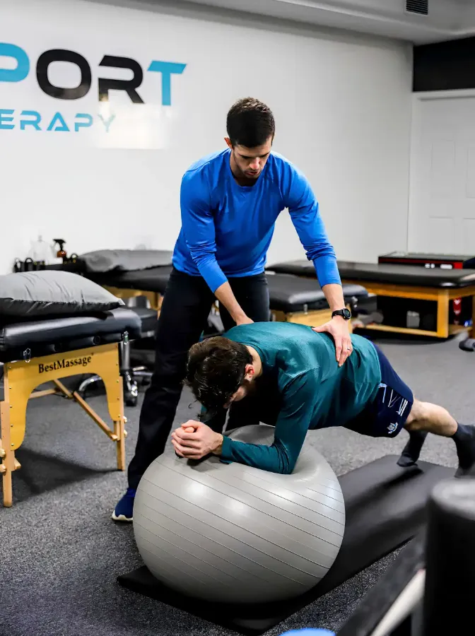 Physical therapist guiding a patient through core stability work on a stability ball at Core Sport and Physical Therapy.