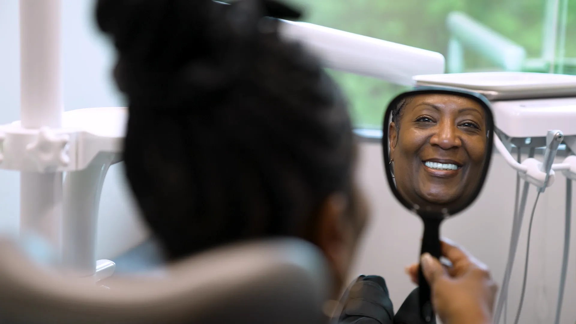 Woman viewing her new smile in a hand mirror