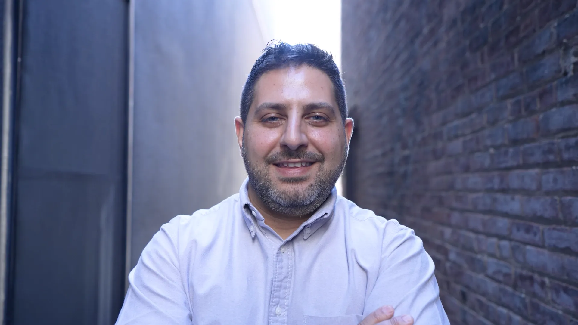 Man smiling against a brick wall