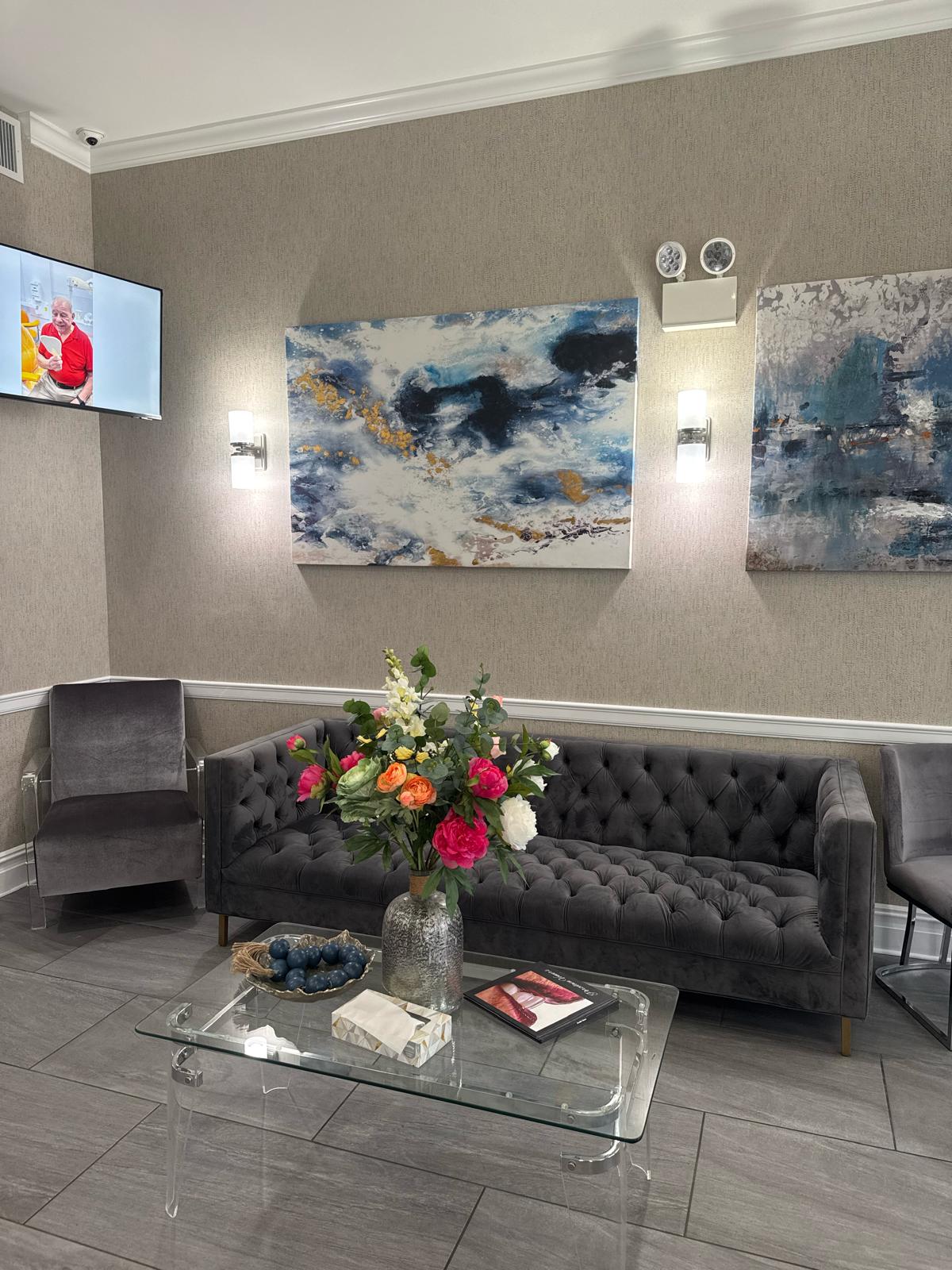 Reception waiting area at Hackensack Center for Dental Implants with gray seating, artwork, and floral arrangement