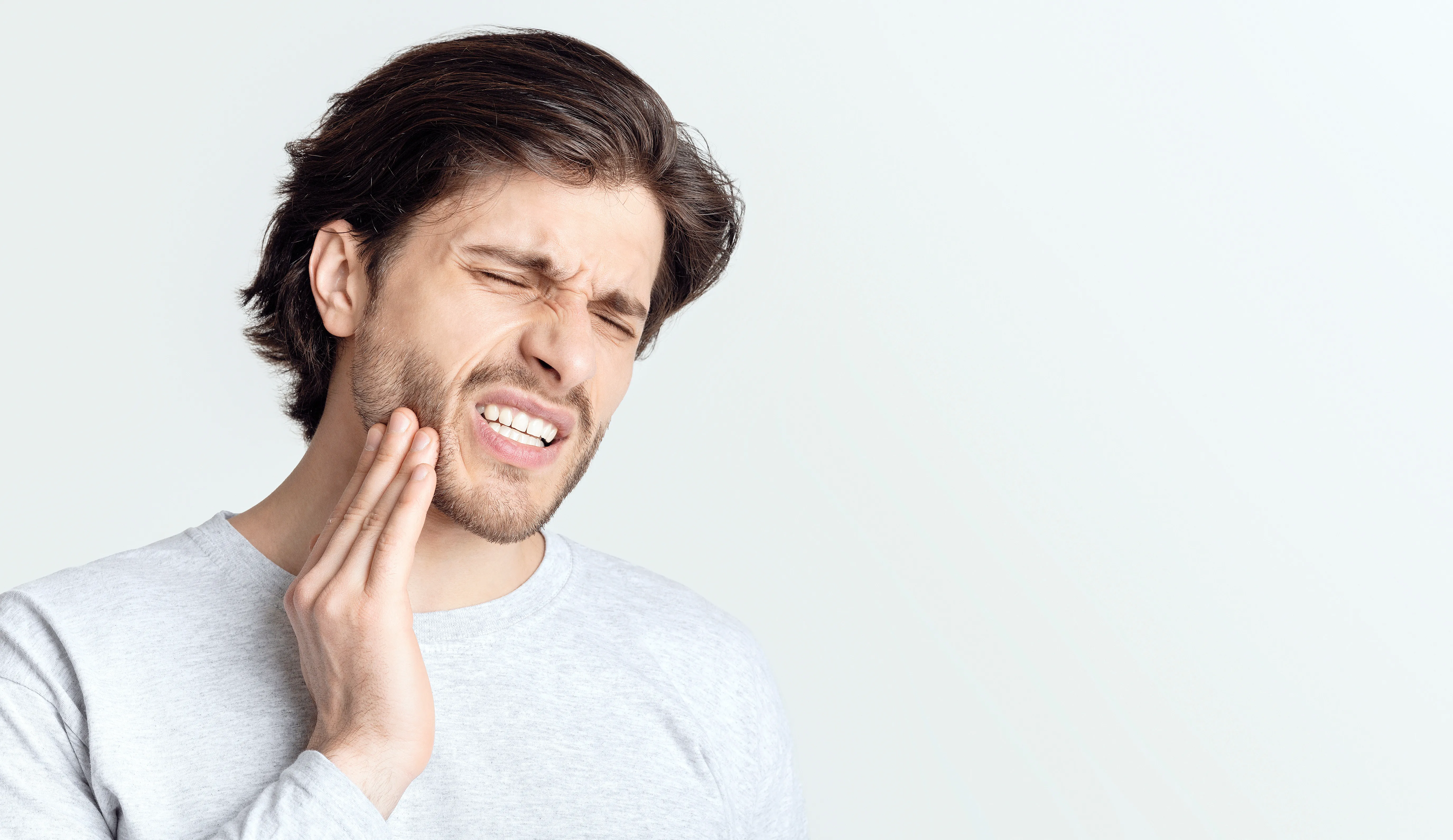 Person touching their jaw because of dental pain