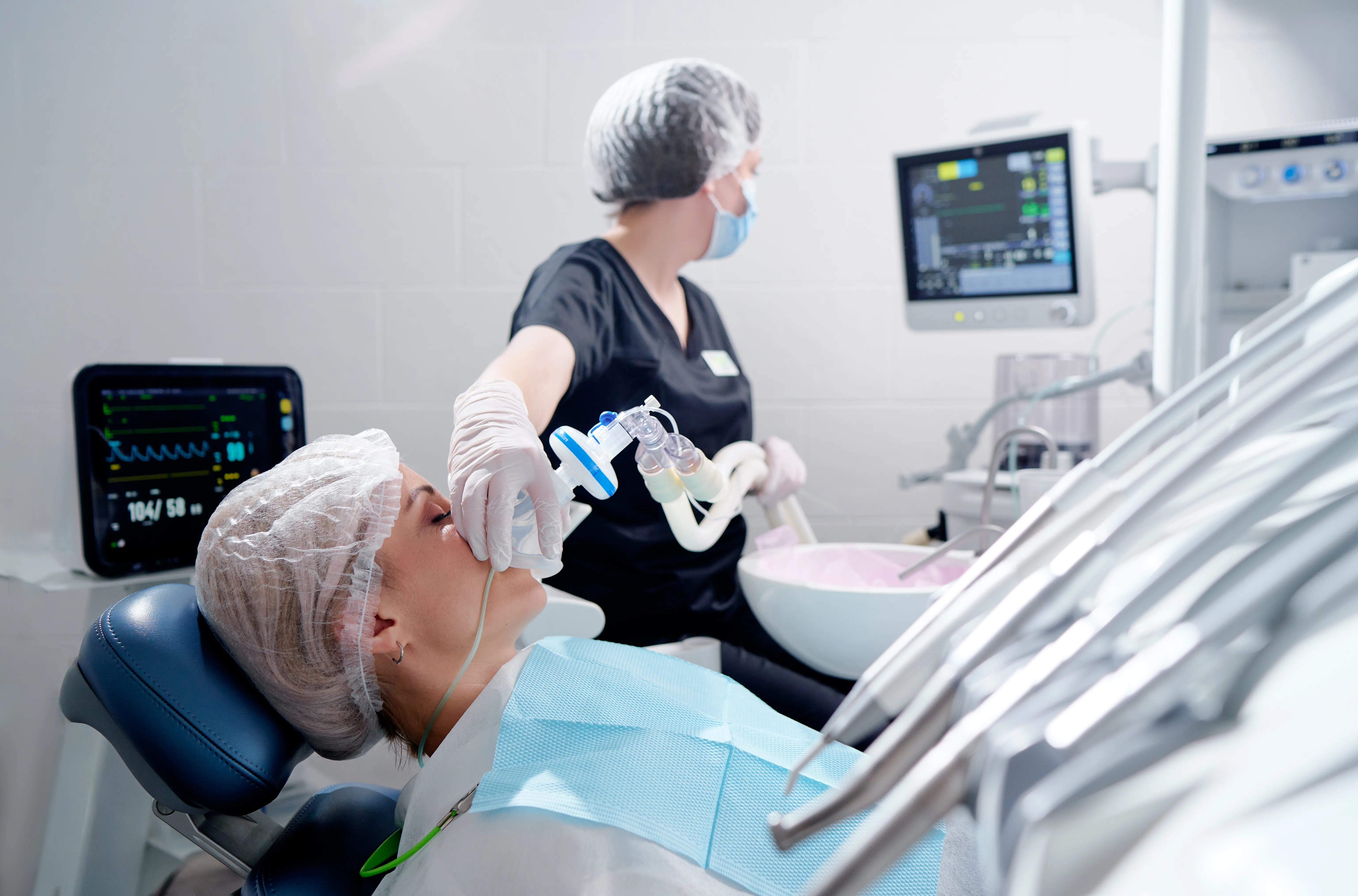 Patient in relaxed state during dental procedure with monitoring equipment visible showing sedation comfort level