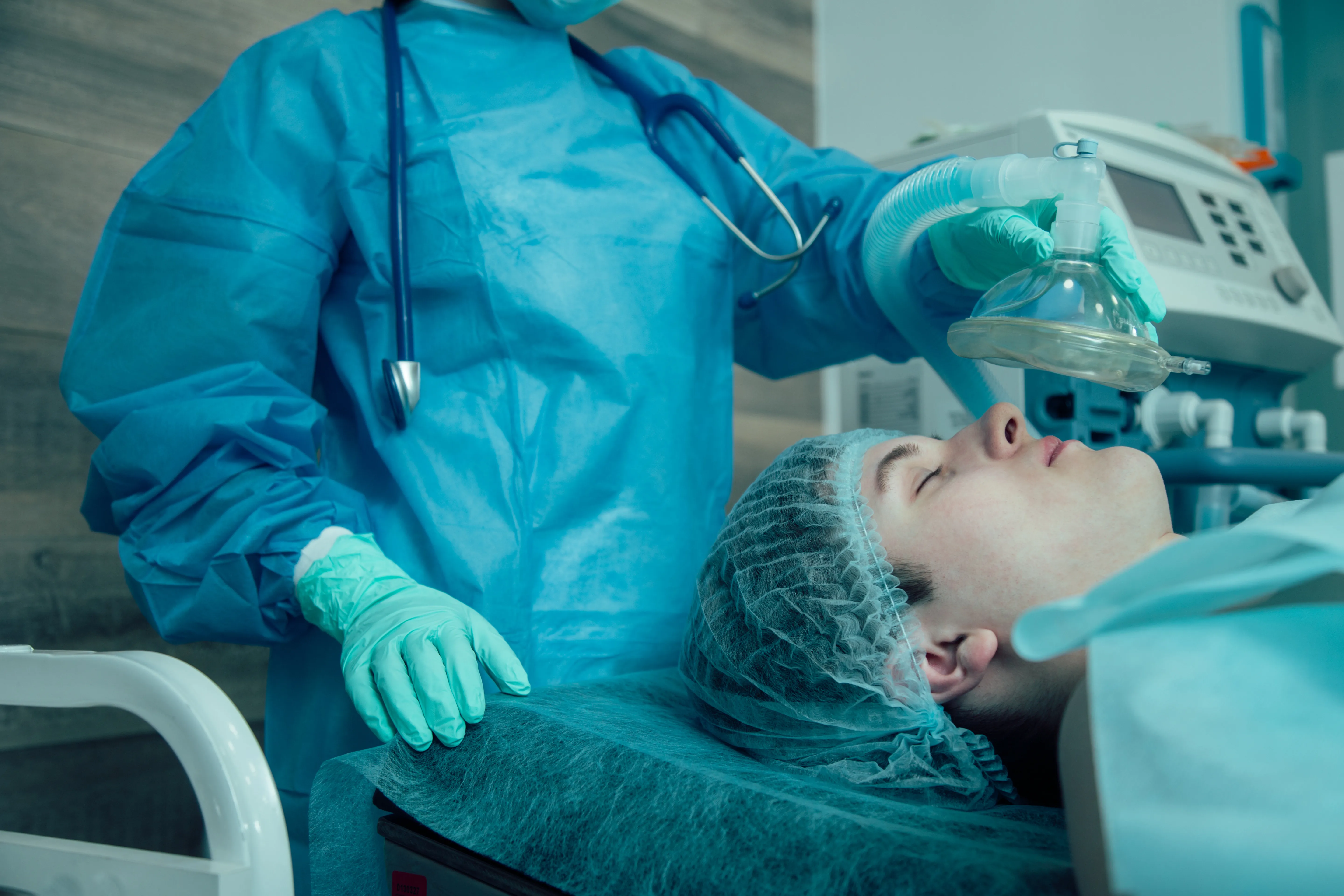 Dental professional in surgical attire preparing patient for sedated implant procedure showing preparation and monitoring