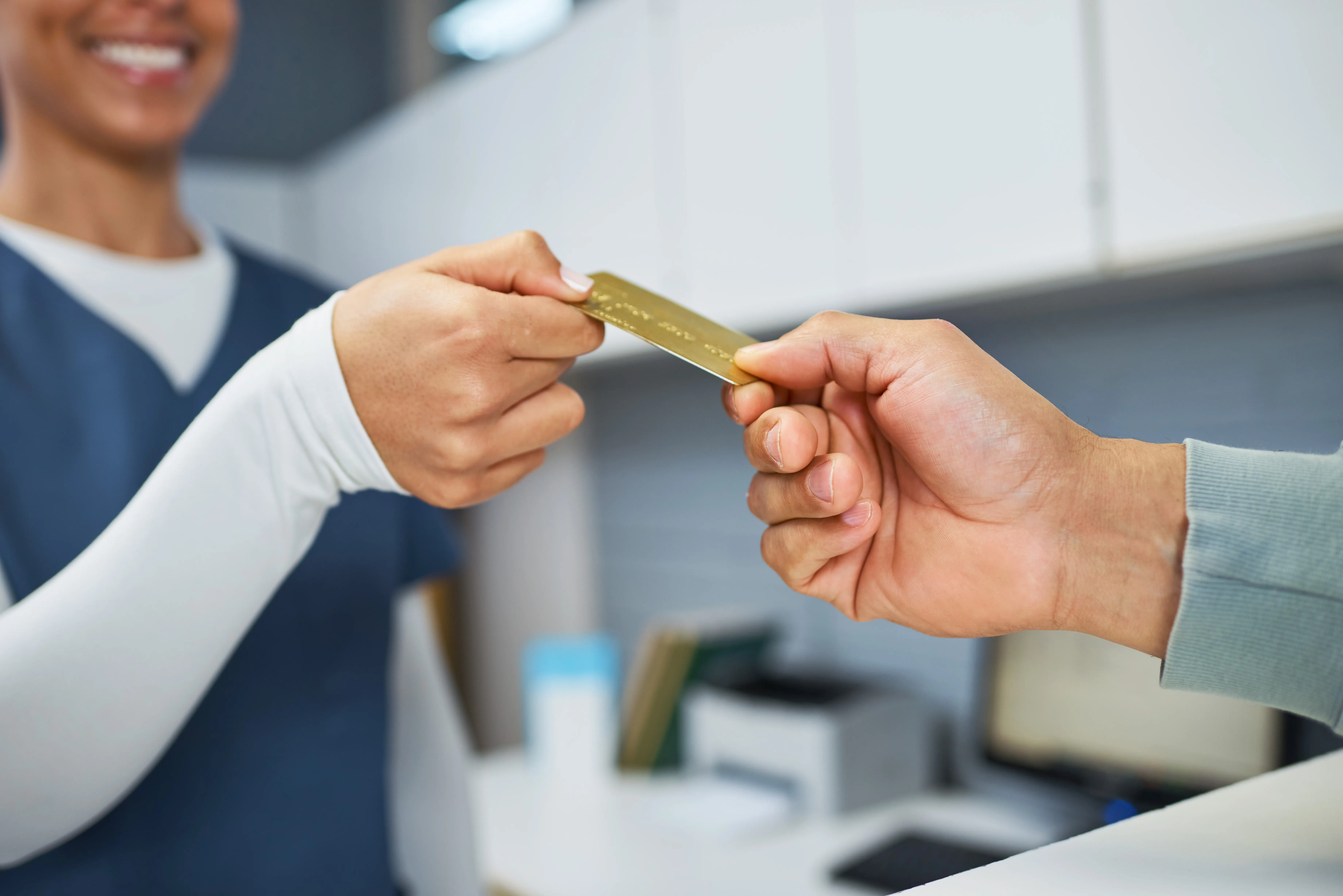 Patient handing a payment card across a counter