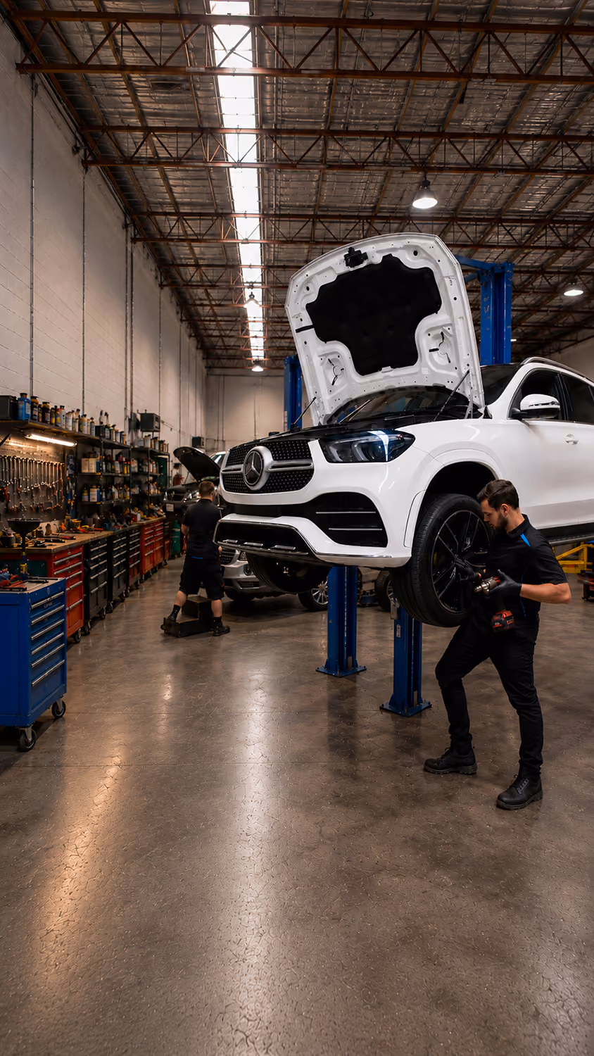 Mechanic working on a red SUV tire lifted in an auto repair shop.