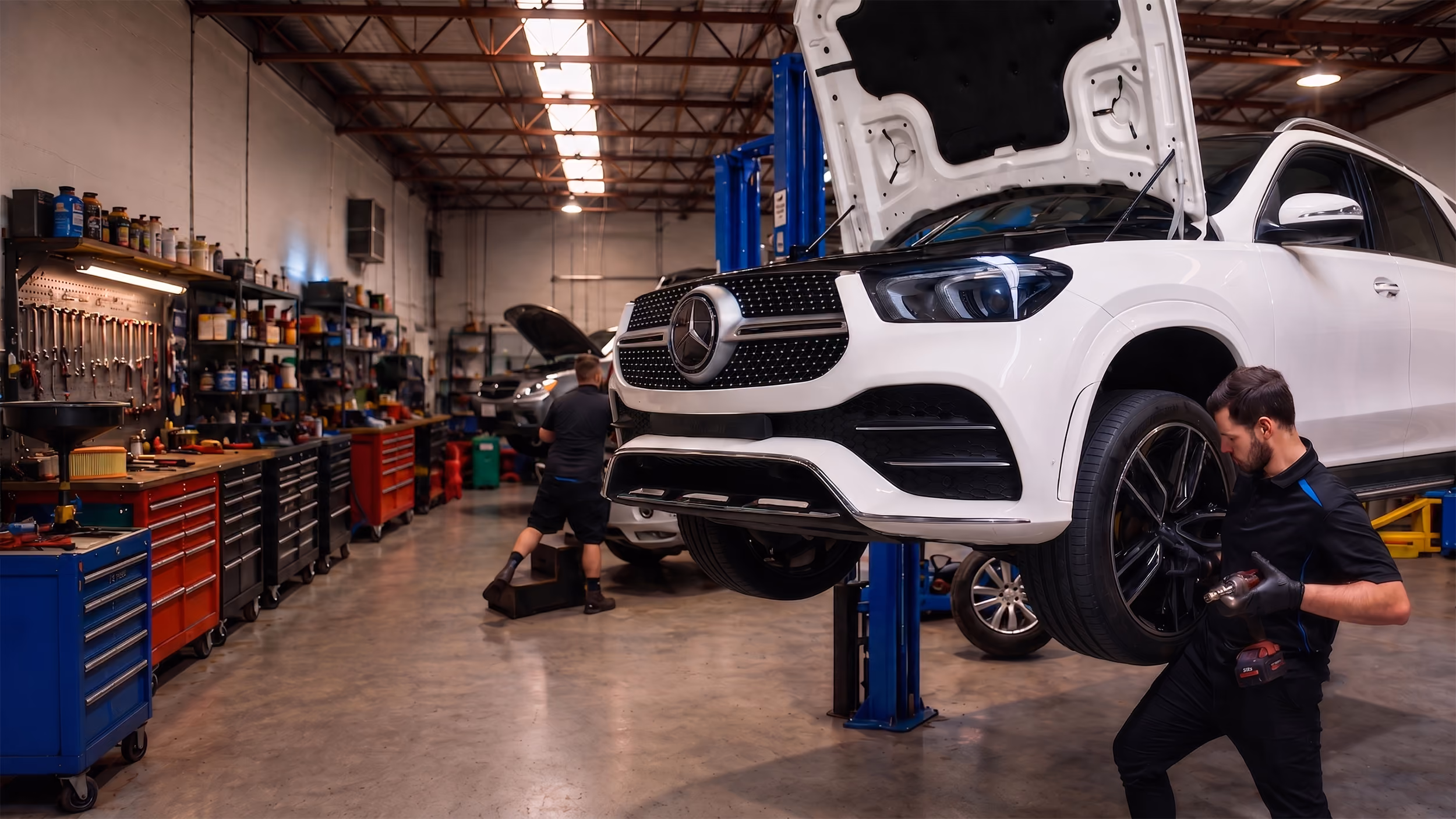 Mechanic working on a red SUV tire lifted in an auto repair shop.