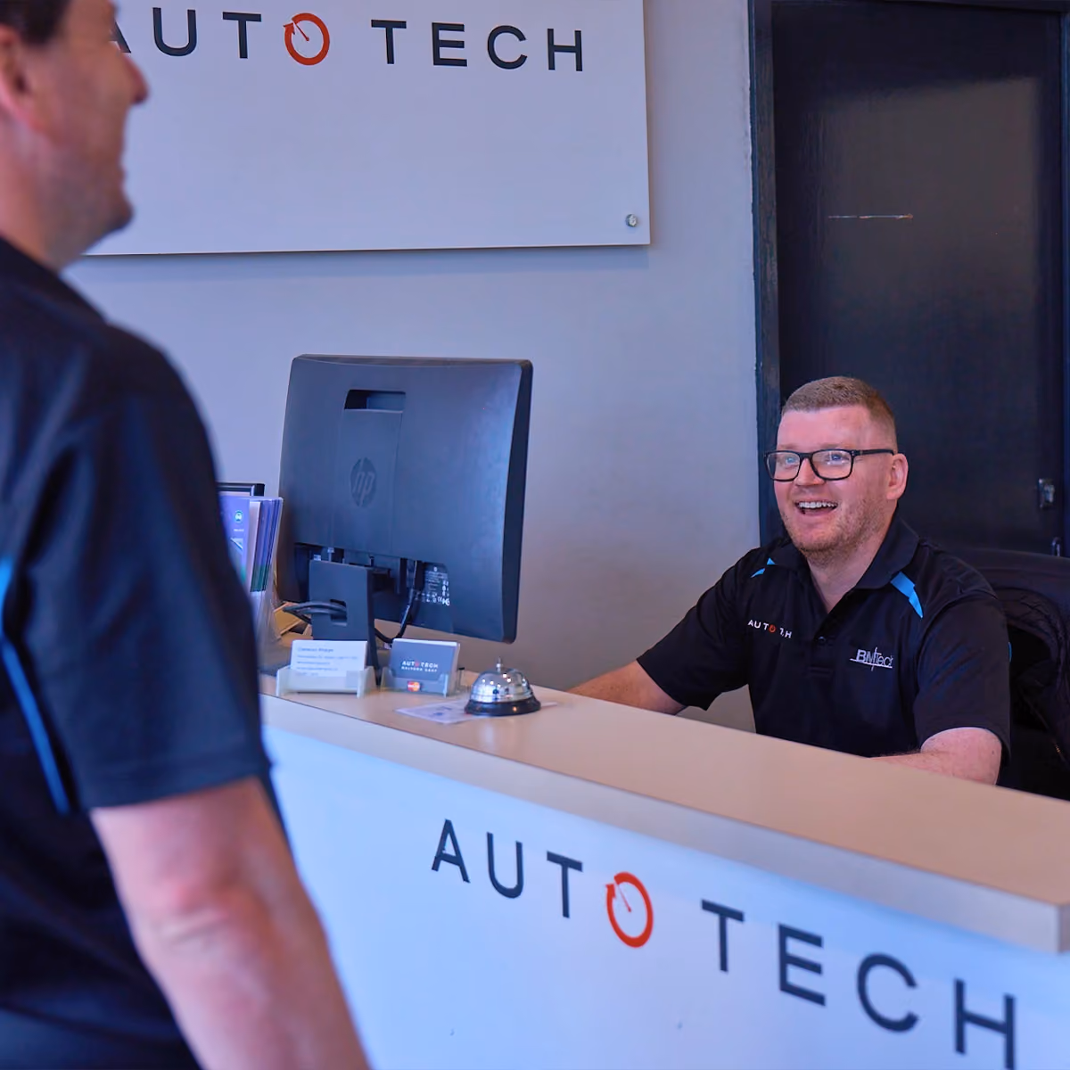 Auto Tech staff member assisting a customer at the workshop reception desk.