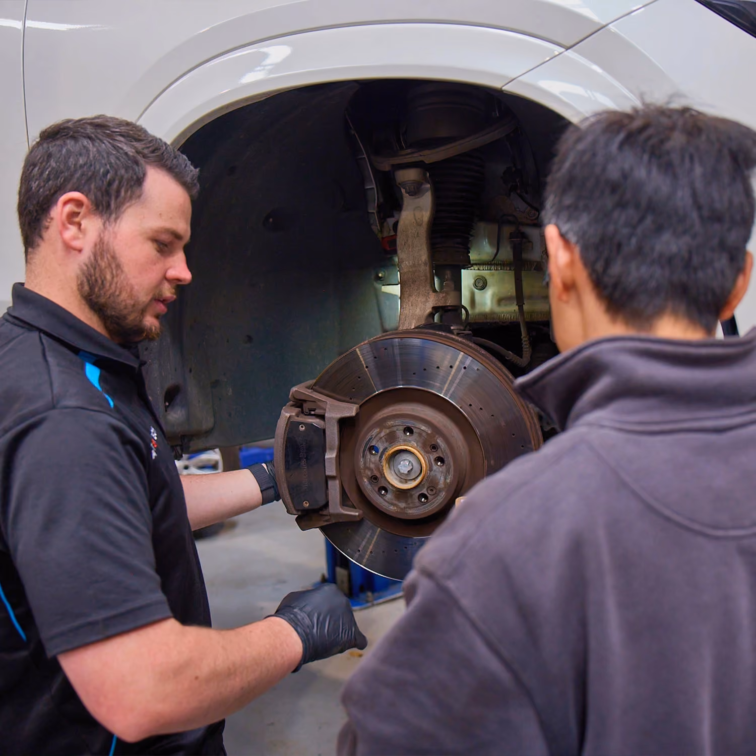 Auto Tech technician explaining brake components during a vehicle inspection.