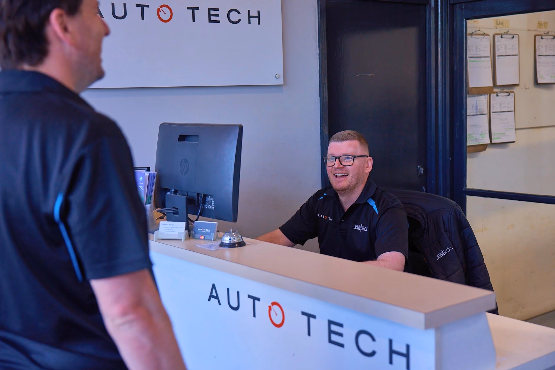Auto Tech Group service advisor assisting customer at reception.