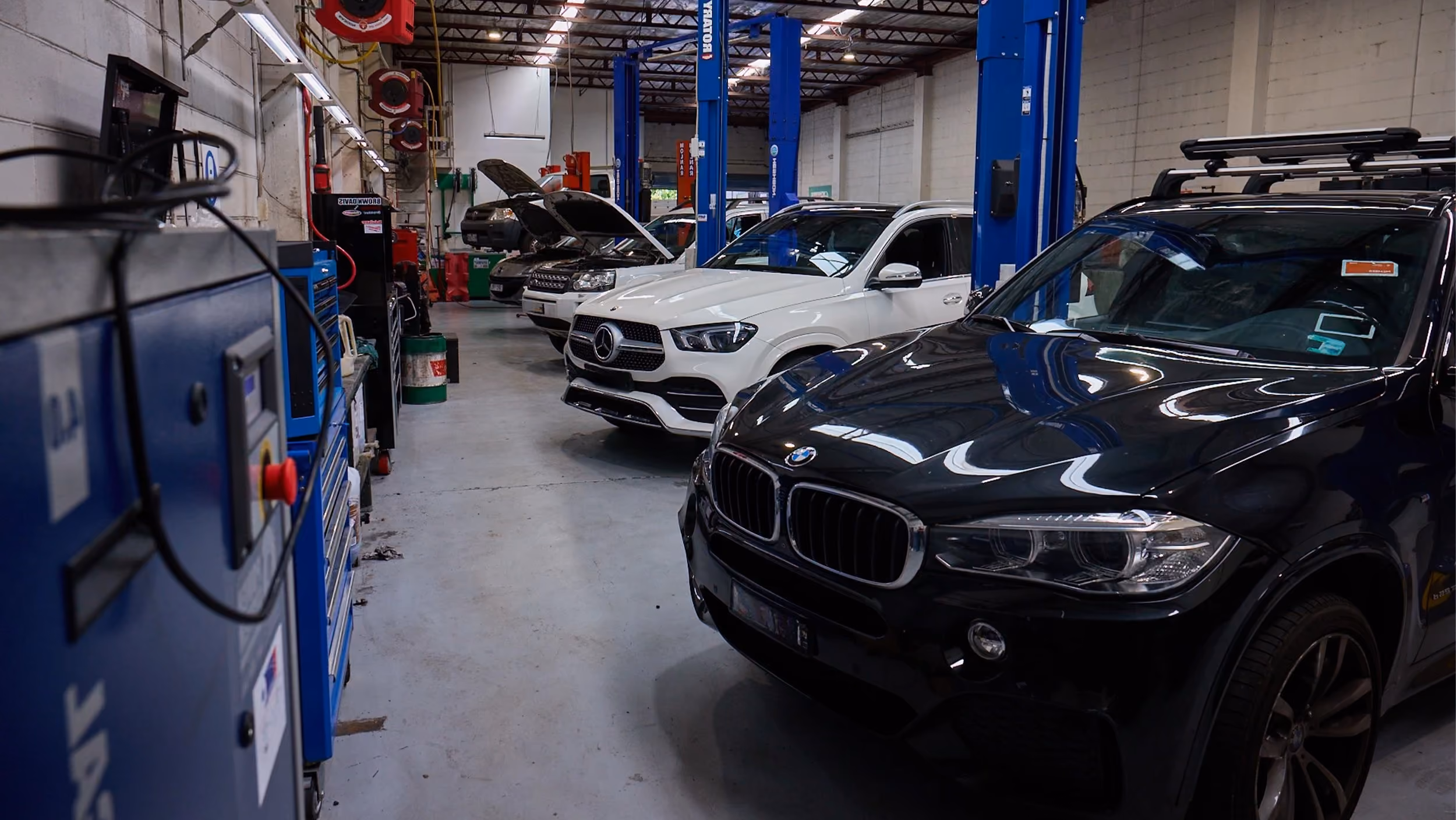 European vehicles being serviced inside Auto Tech Group workshop with hoists and diagnostic equipment.