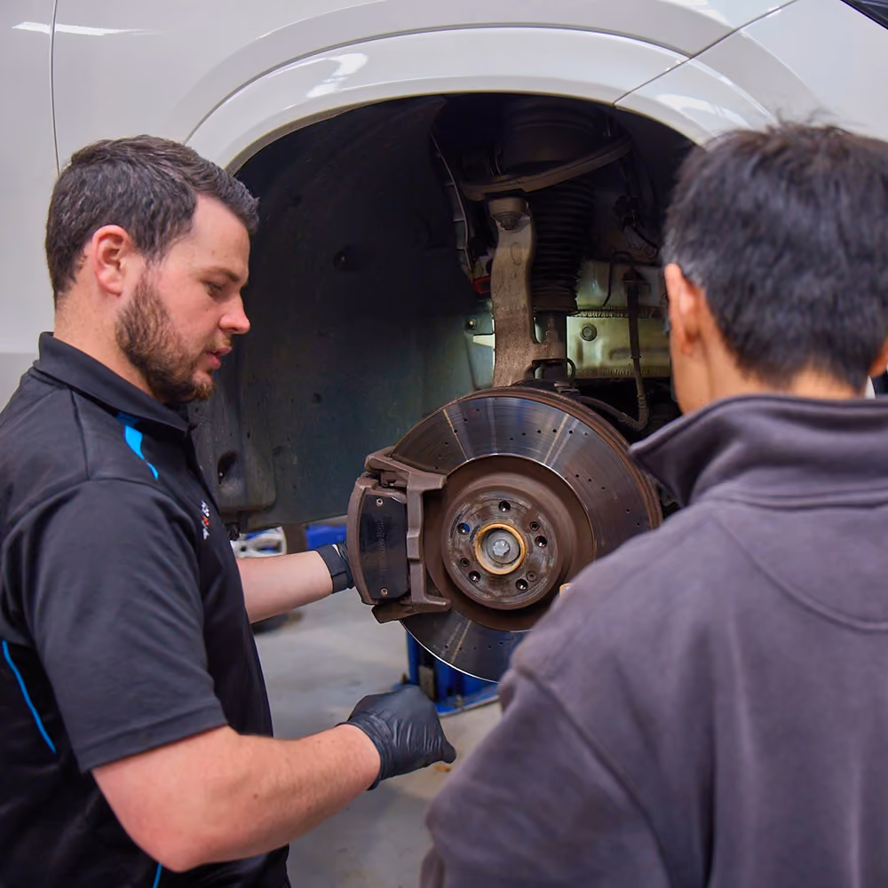 Technician explaining brake system components to customer during inspection