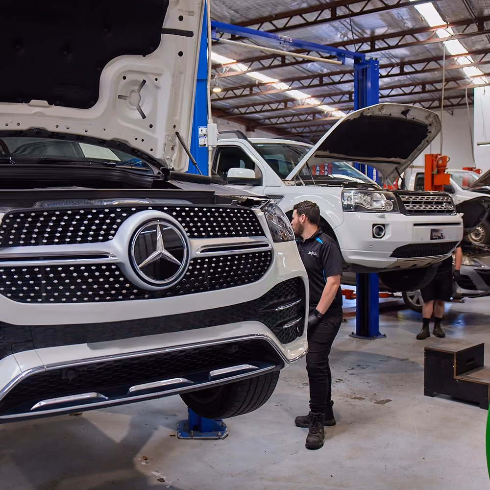 European car being serviced in workshop with technician nearby.