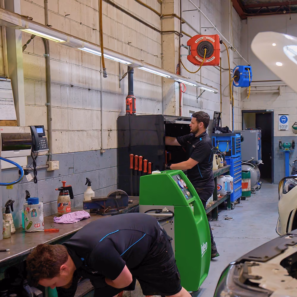 Mechanics working on vehicles using workshop equipment during service
