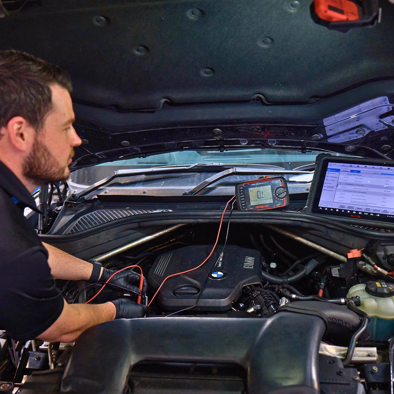 Mechanic diagnosing BMW engine using diagnostic tools.
