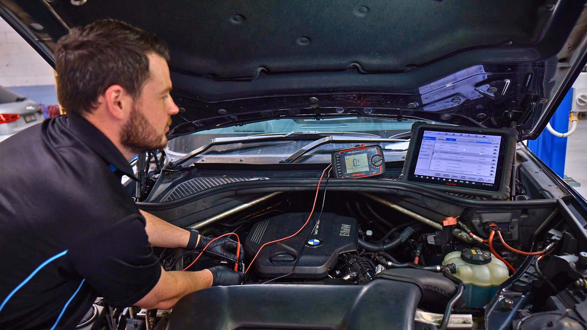 Technician running diagnostics on car engine during logbook service.