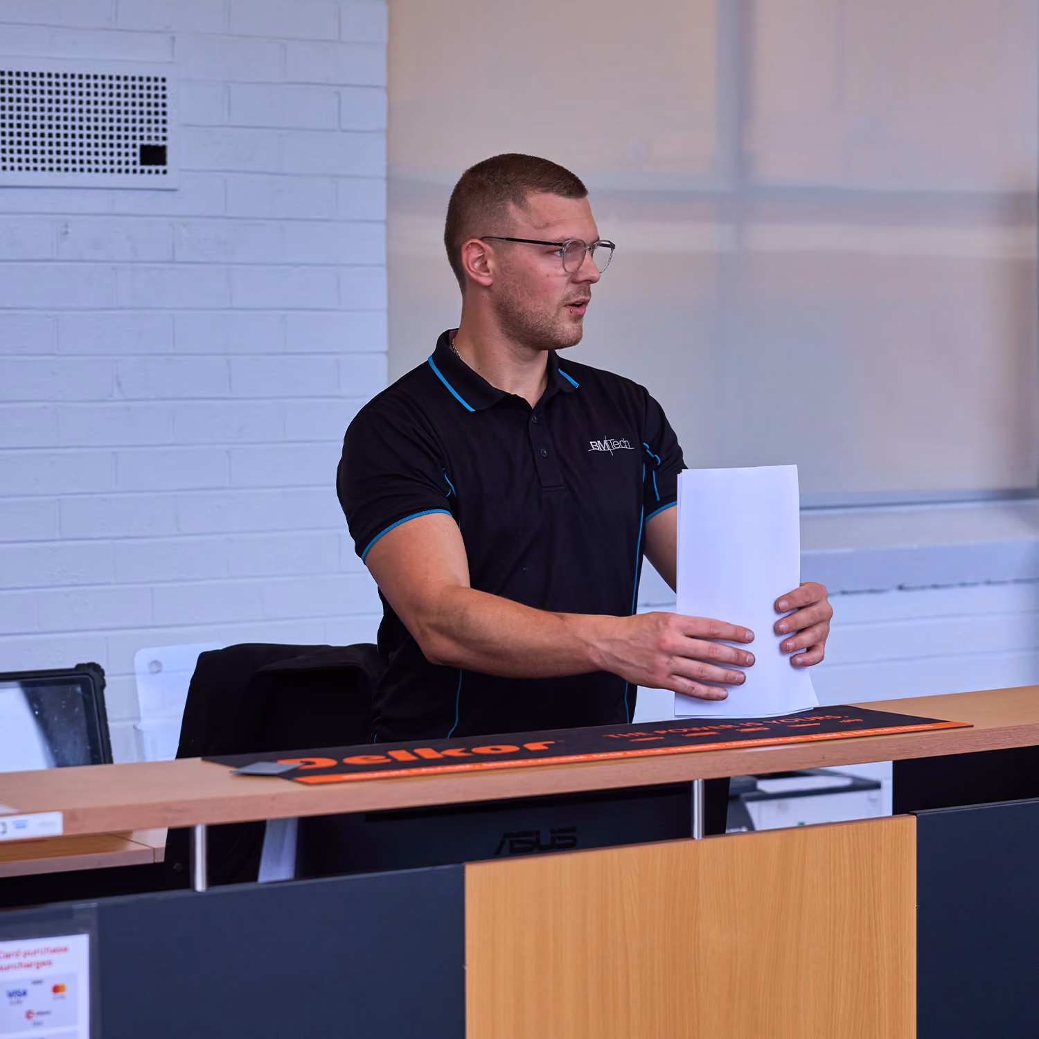 Auto Tech Group staff member assisting customer at workshop reception desk.